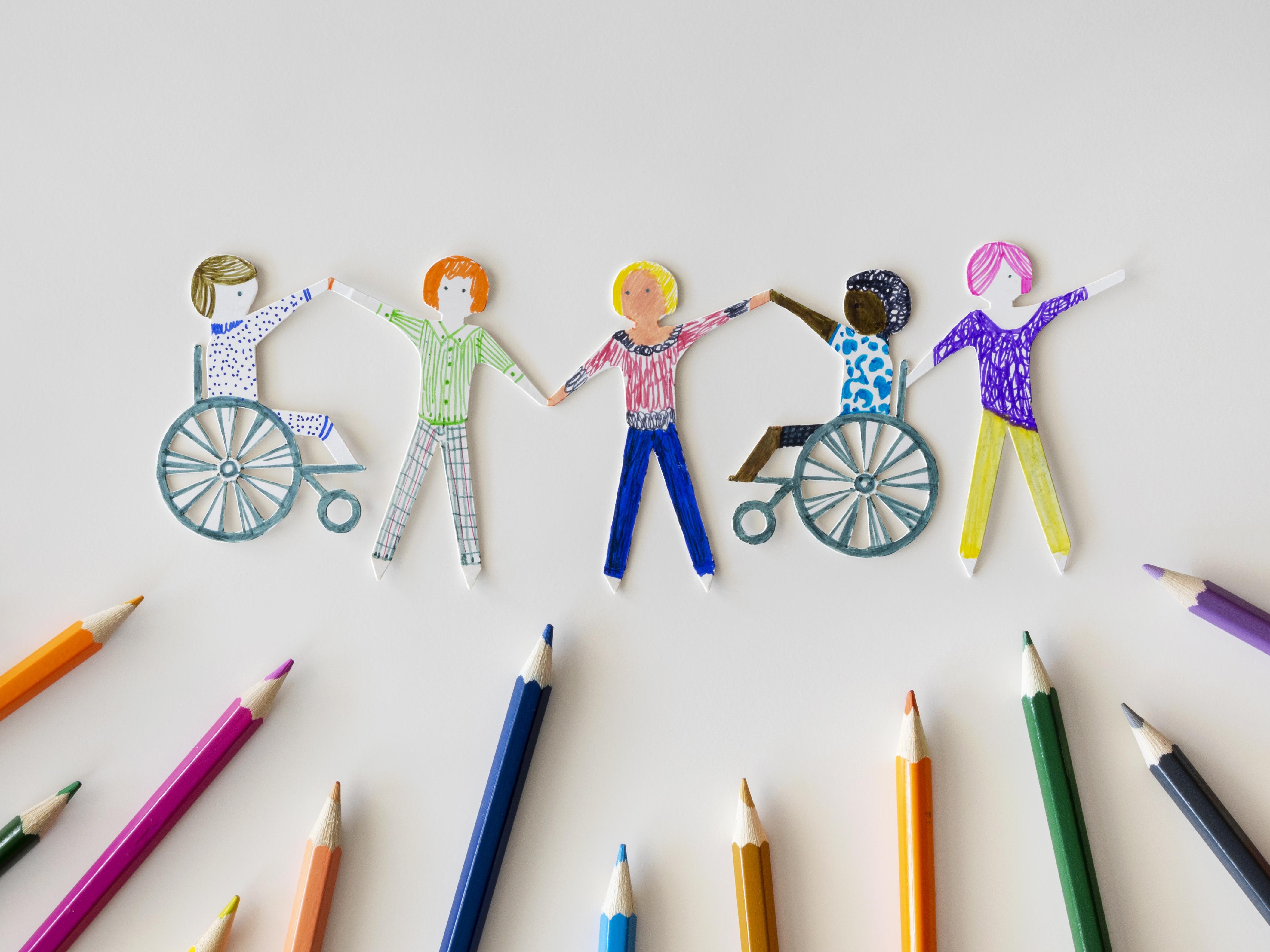 Imagem mostra lápis de cor e desenhos de pessoas com alguma deficiência, simbolizando acessibilidade e inclusividade