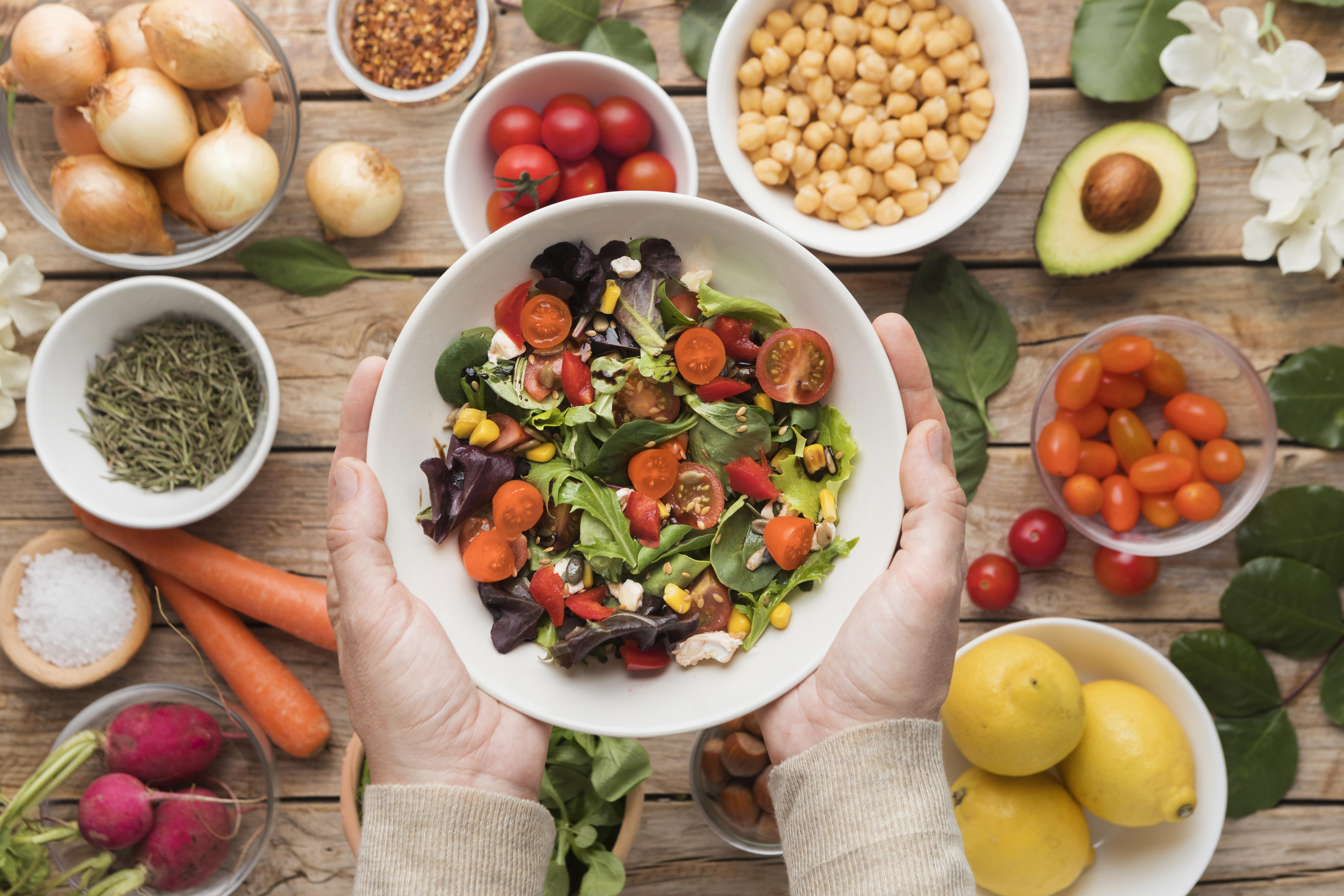 Vista superior de ingredientes e legumes em um prato de salada. Em volta, estão pequenas vasilhas com alimentos deste contexto