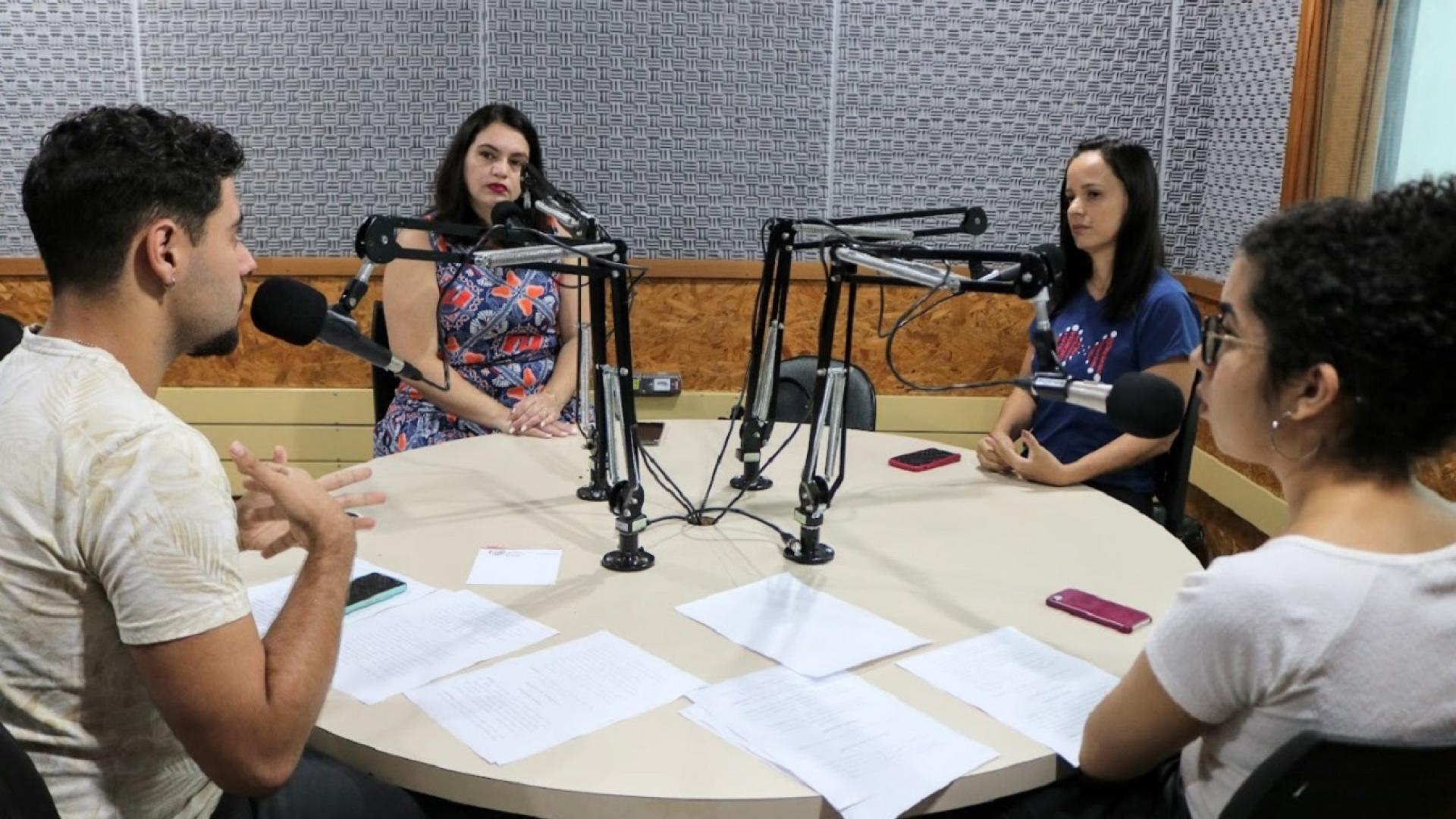 Quatro pessoas realizando gravações de um podcast num estúdio de áudio